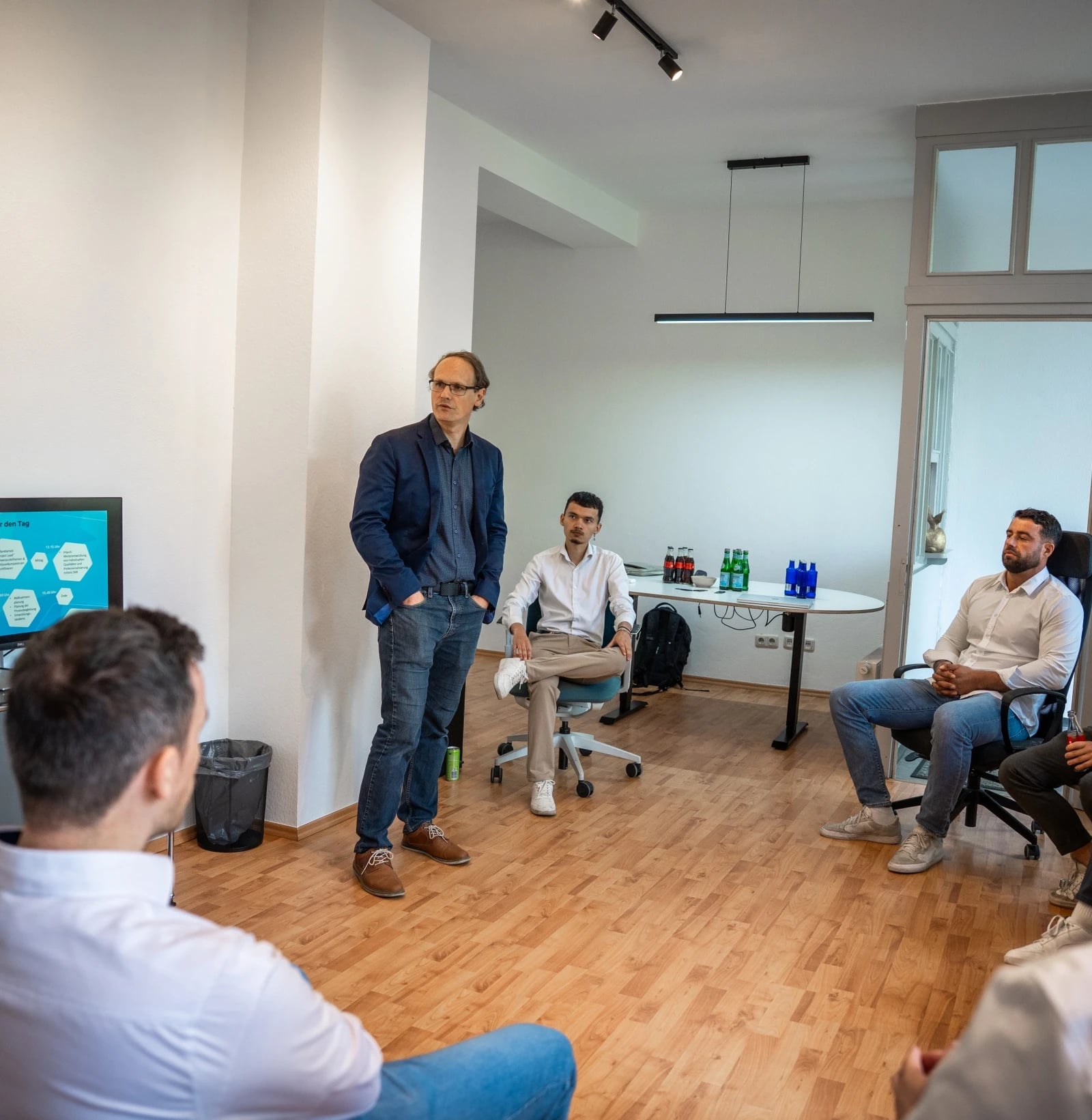 Mann präsentiert vor kleinem Team im Büro