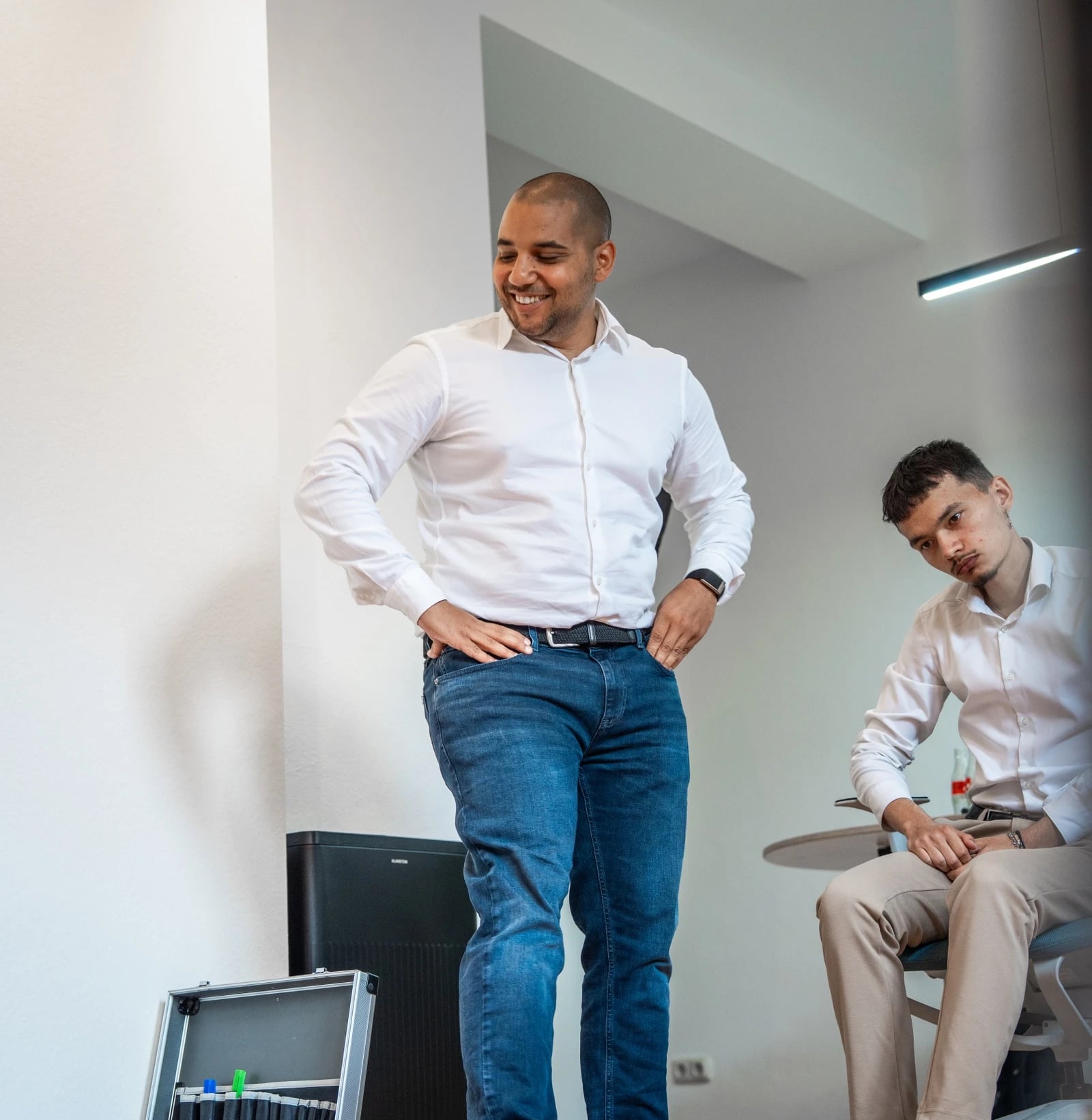 Zwei Männer im Büro, einer steht lächelnd