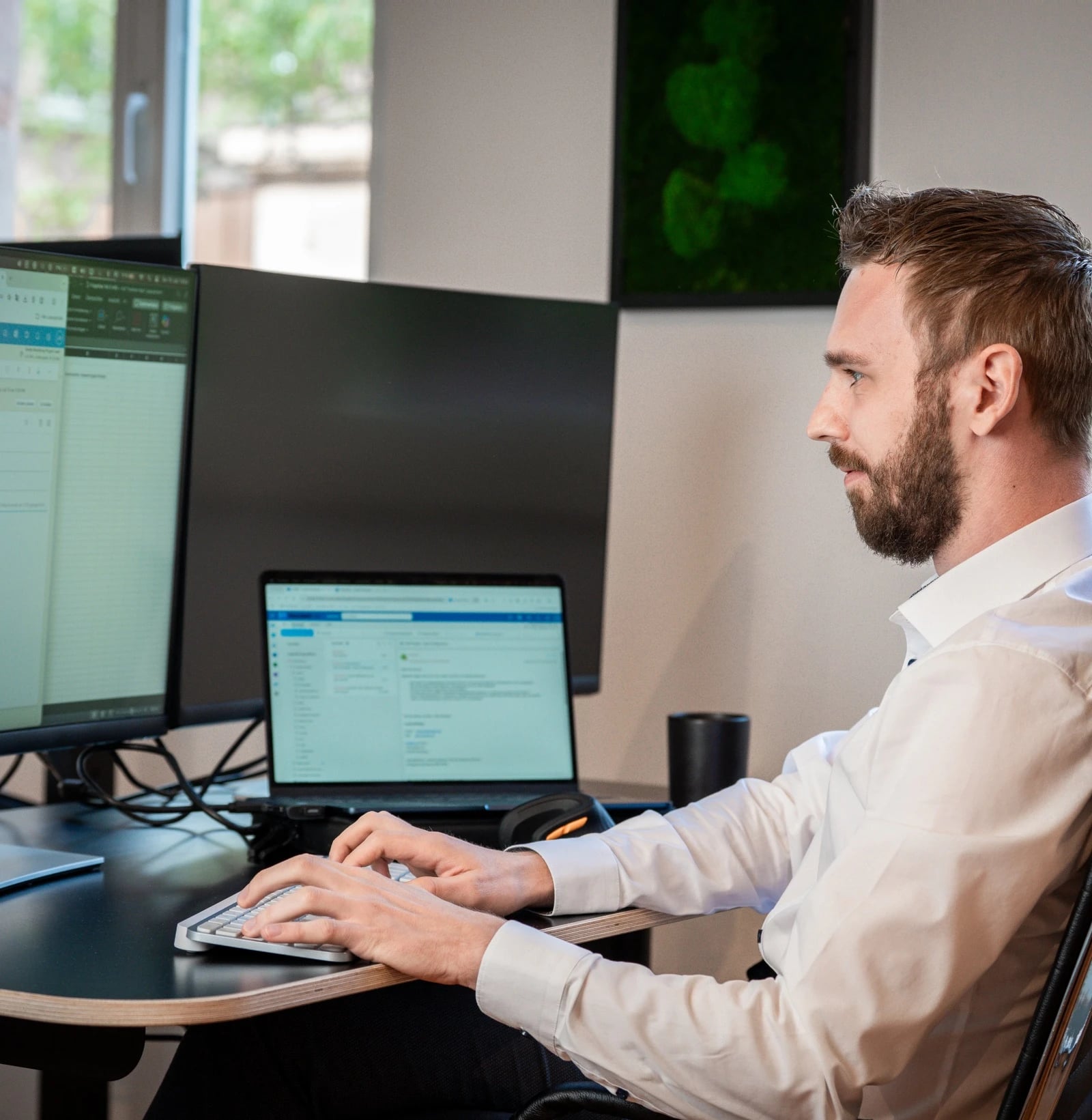 Mann arbeitet am Schreibtisch mit mehreren Monitoren