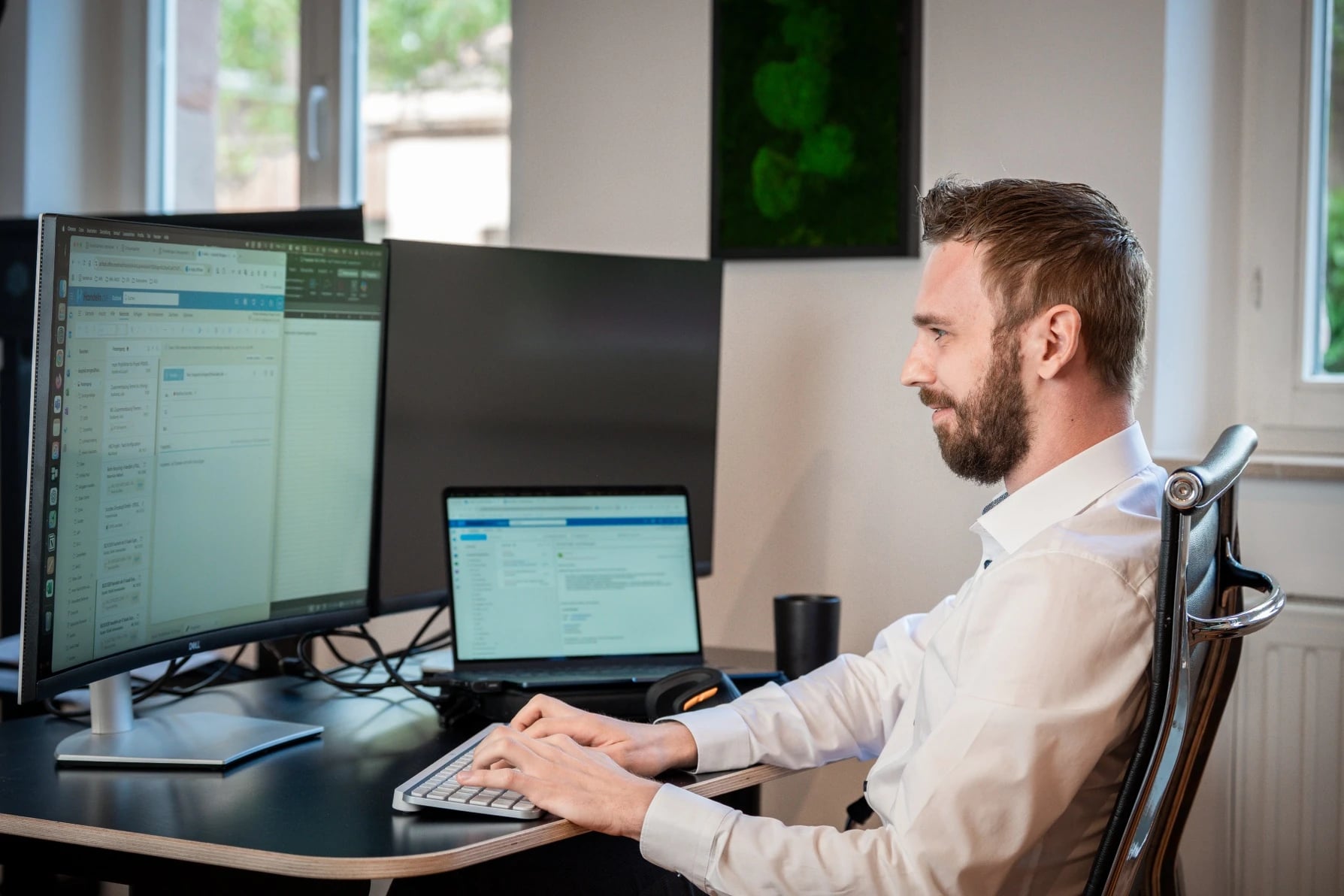 Mann arbeitet am Schreibtisch mit zwei Monitoren