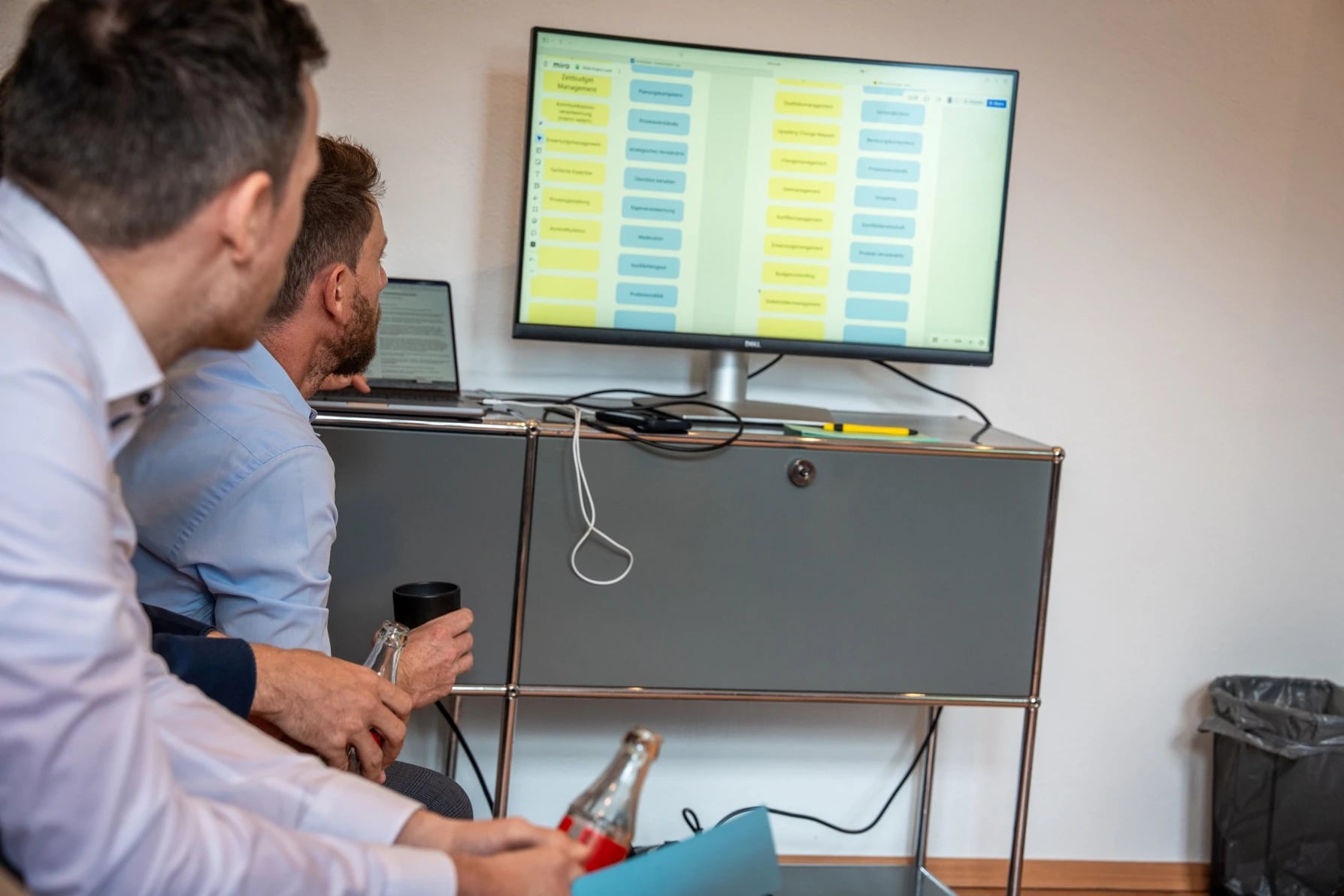 Zwei Männer betrachten Kanban-Board am Monitor