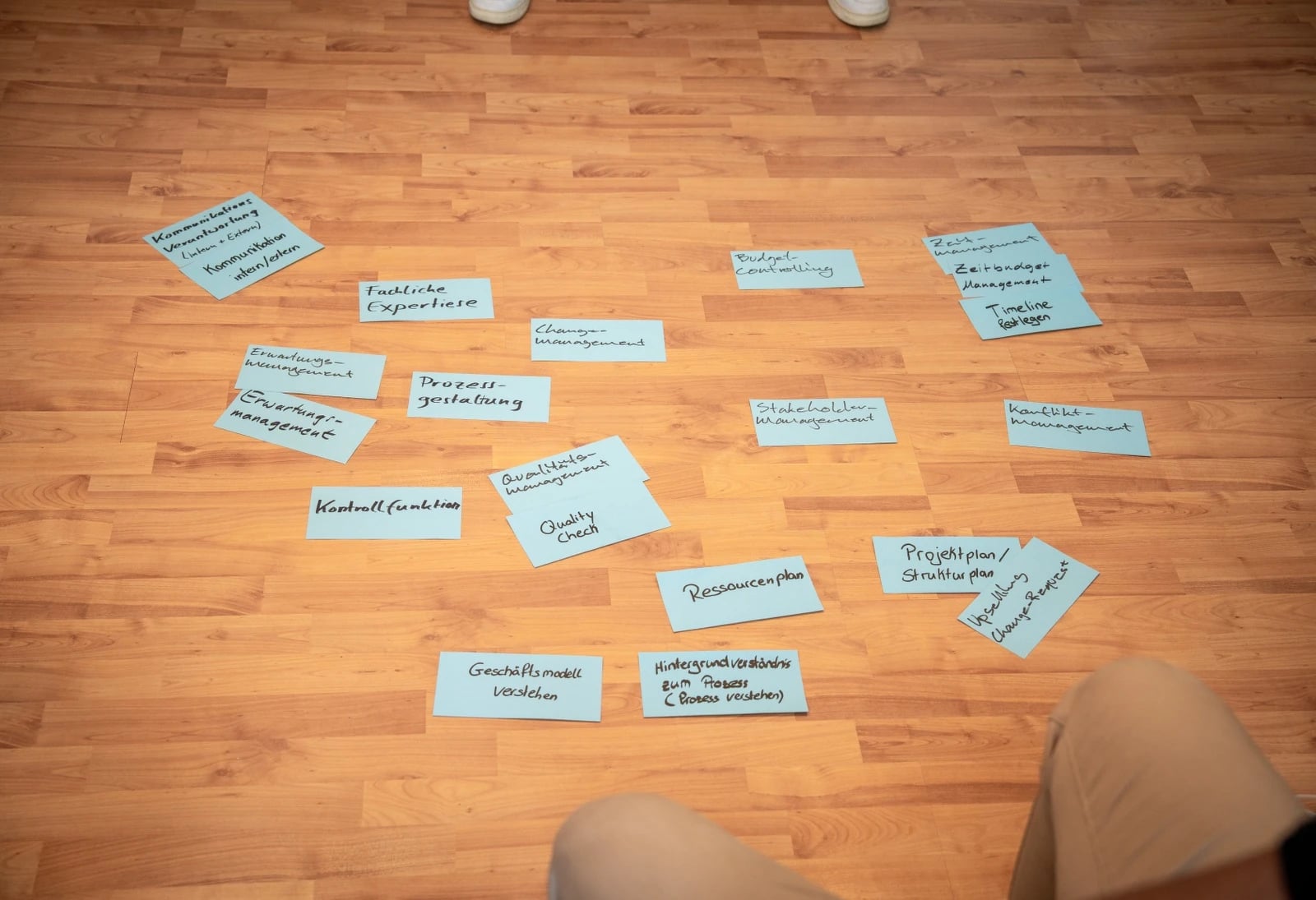 Moderationskarten zu Projektmanagement-Kompetenzen auf Holzboden