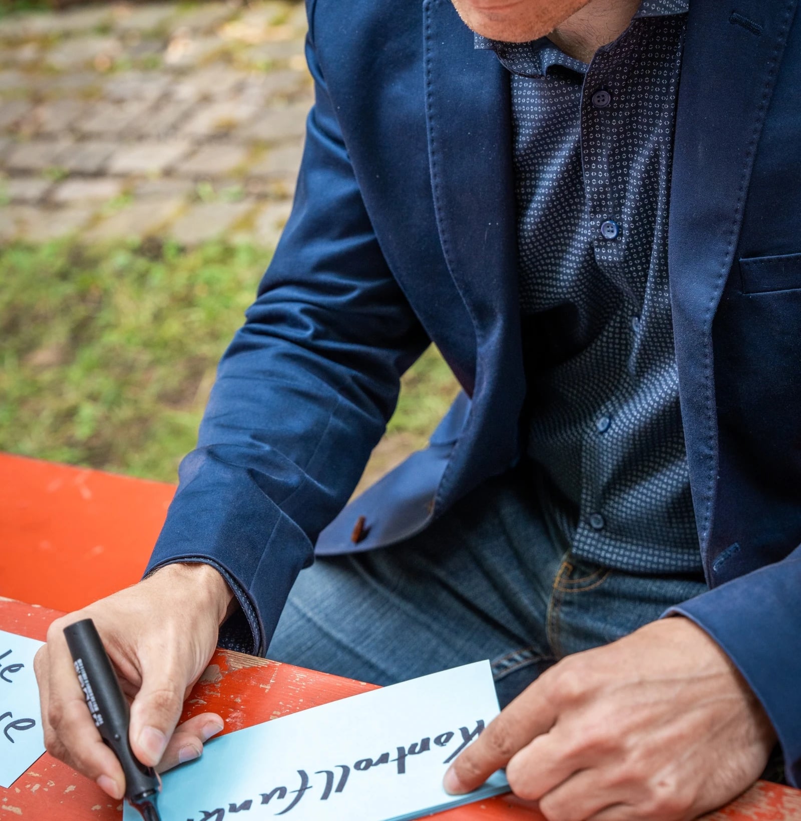 Mann schreibt Notiz an rotem Tisch