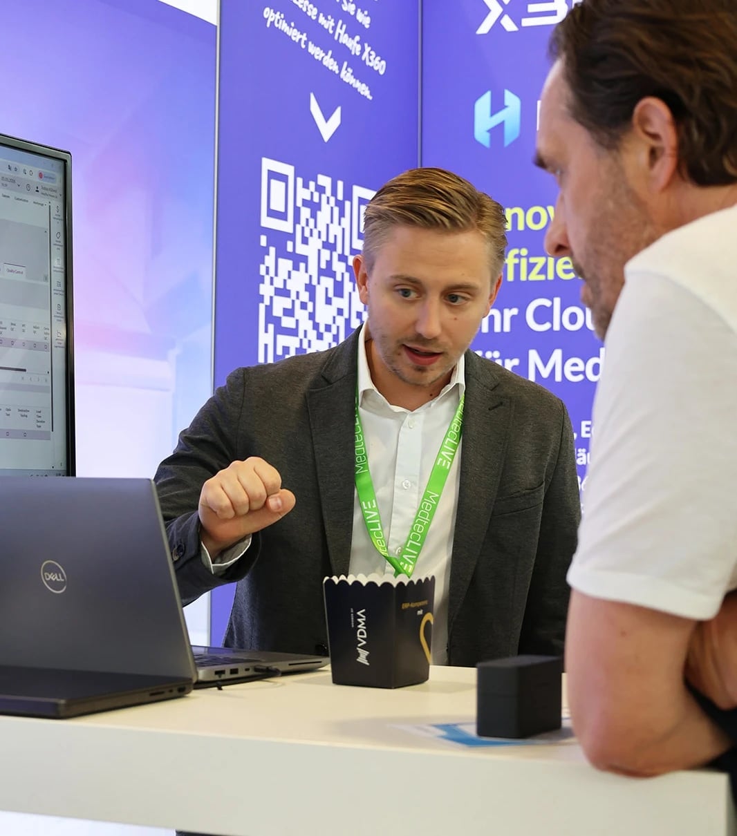 Beratungsgespräch am Messestand mit Laptop und QR-Code