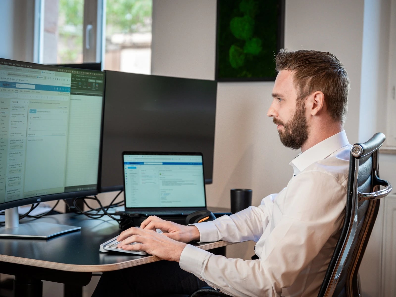 Mann arbeitet am Schreibtisch mit mehreren Monitoren