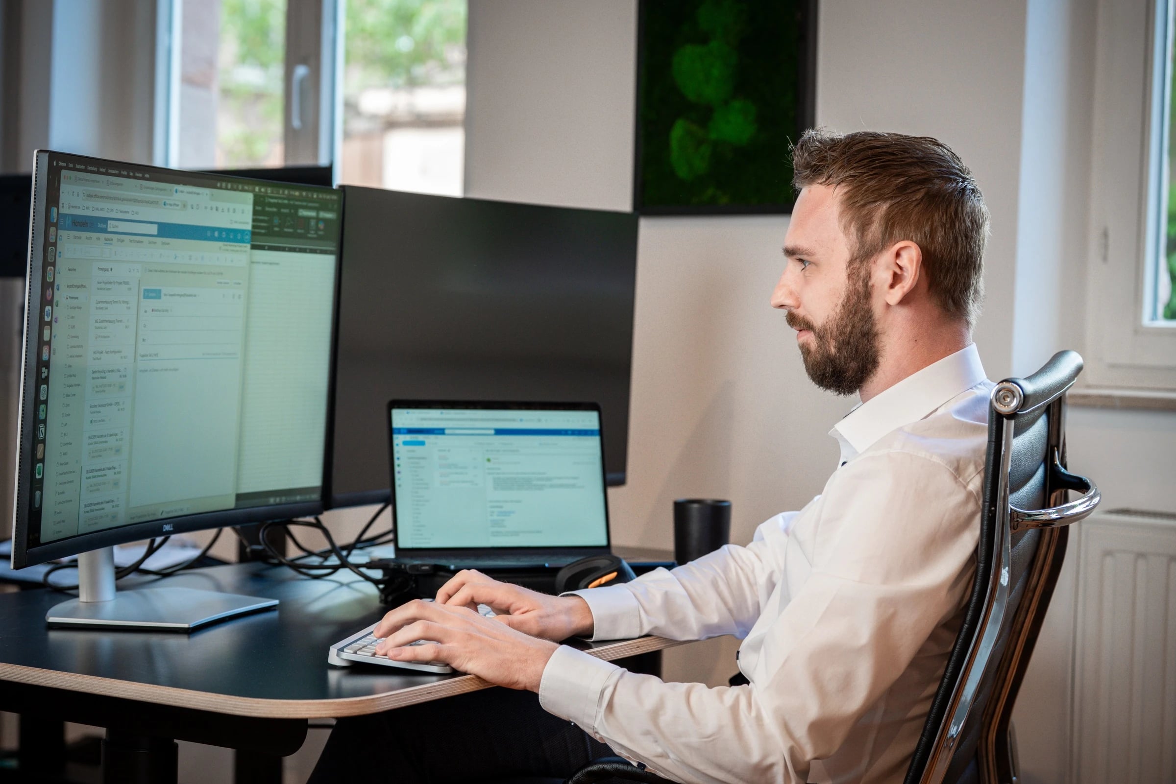 Mann arbeitet am Schreibtisch mit großem Monitor