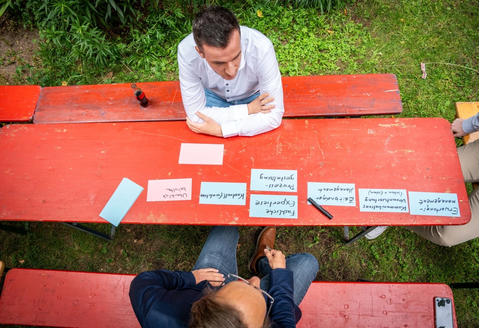 Zwei Männer brainstormen am roten Picknicktisch