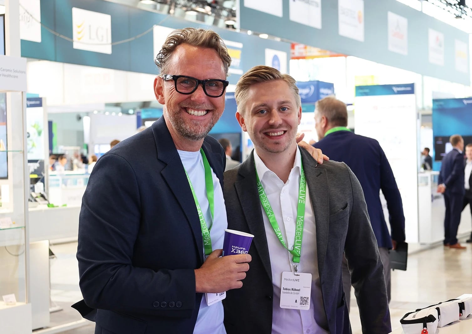 Zwei Männer auf einer Fachmesse lächelnd