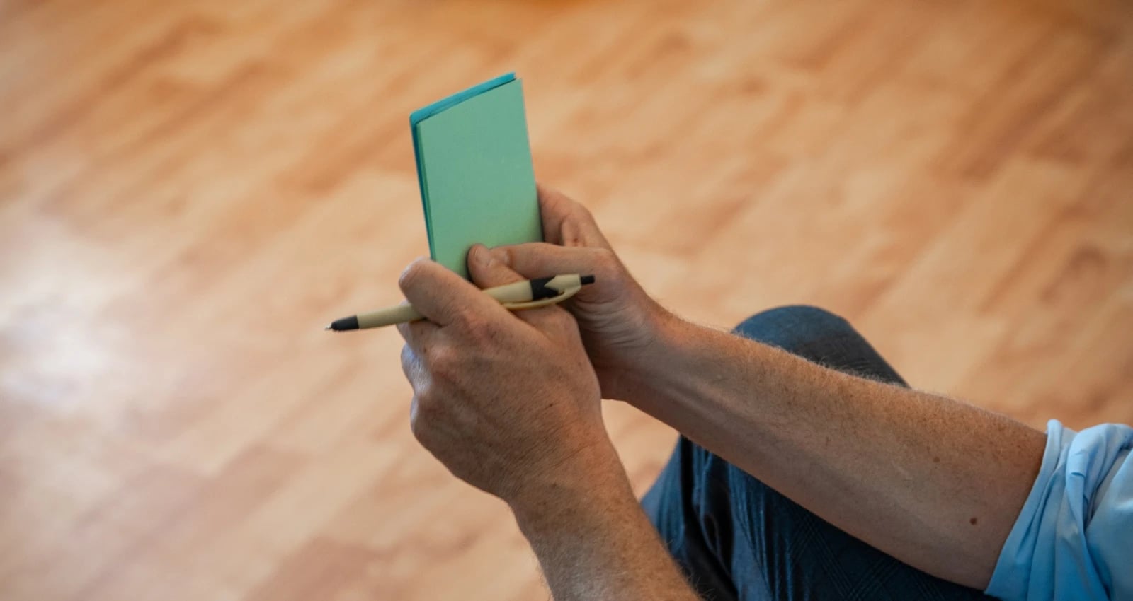 Person schreibt in kleines grünes Notizbuch