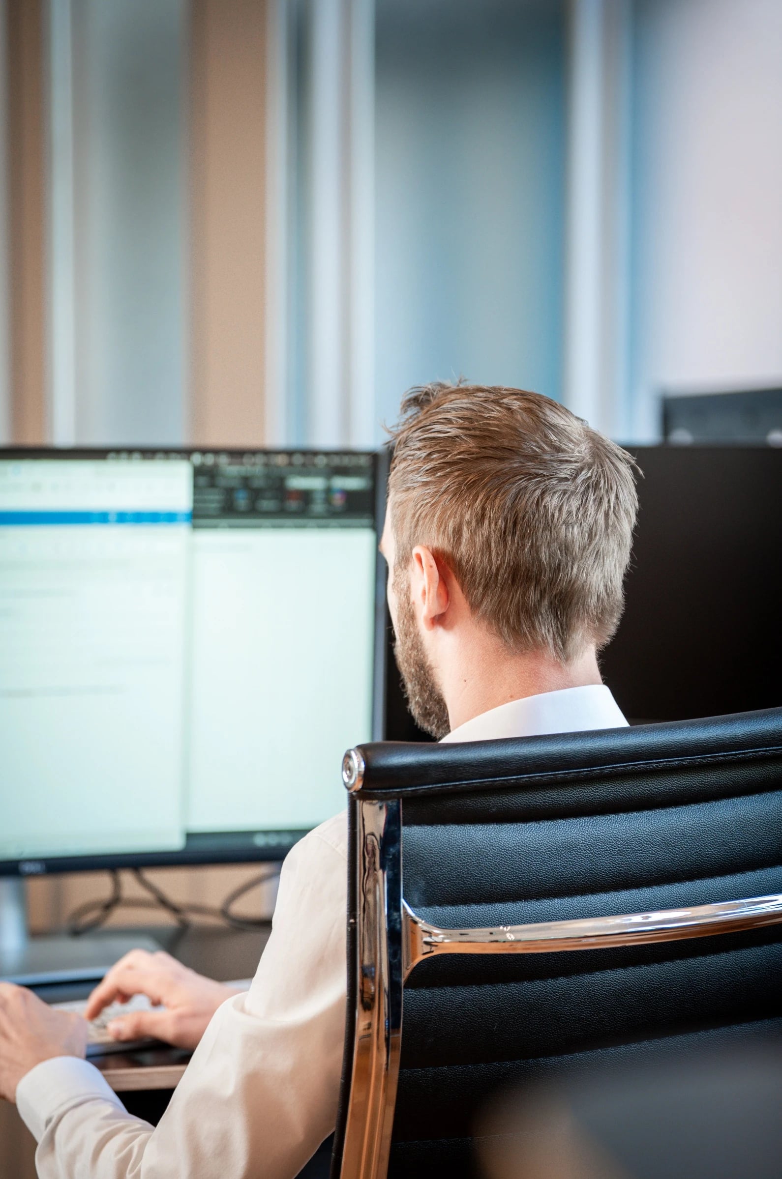Mitarbeiter arbeitet im Büro an zwei Bildschirmen