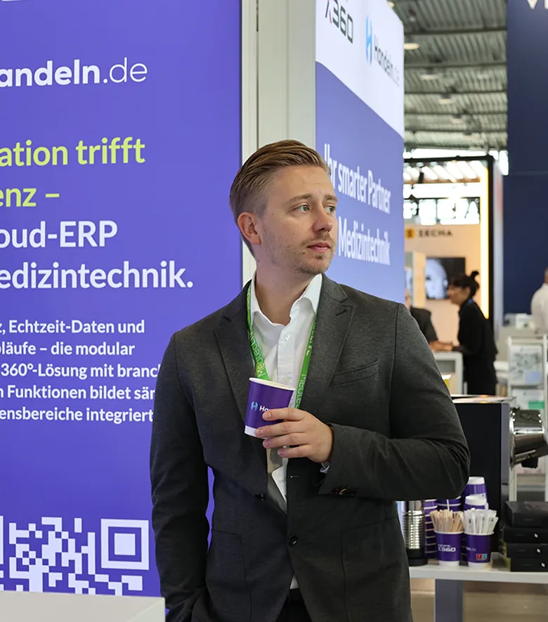 Mann am Messestand mit Kaffeebecher