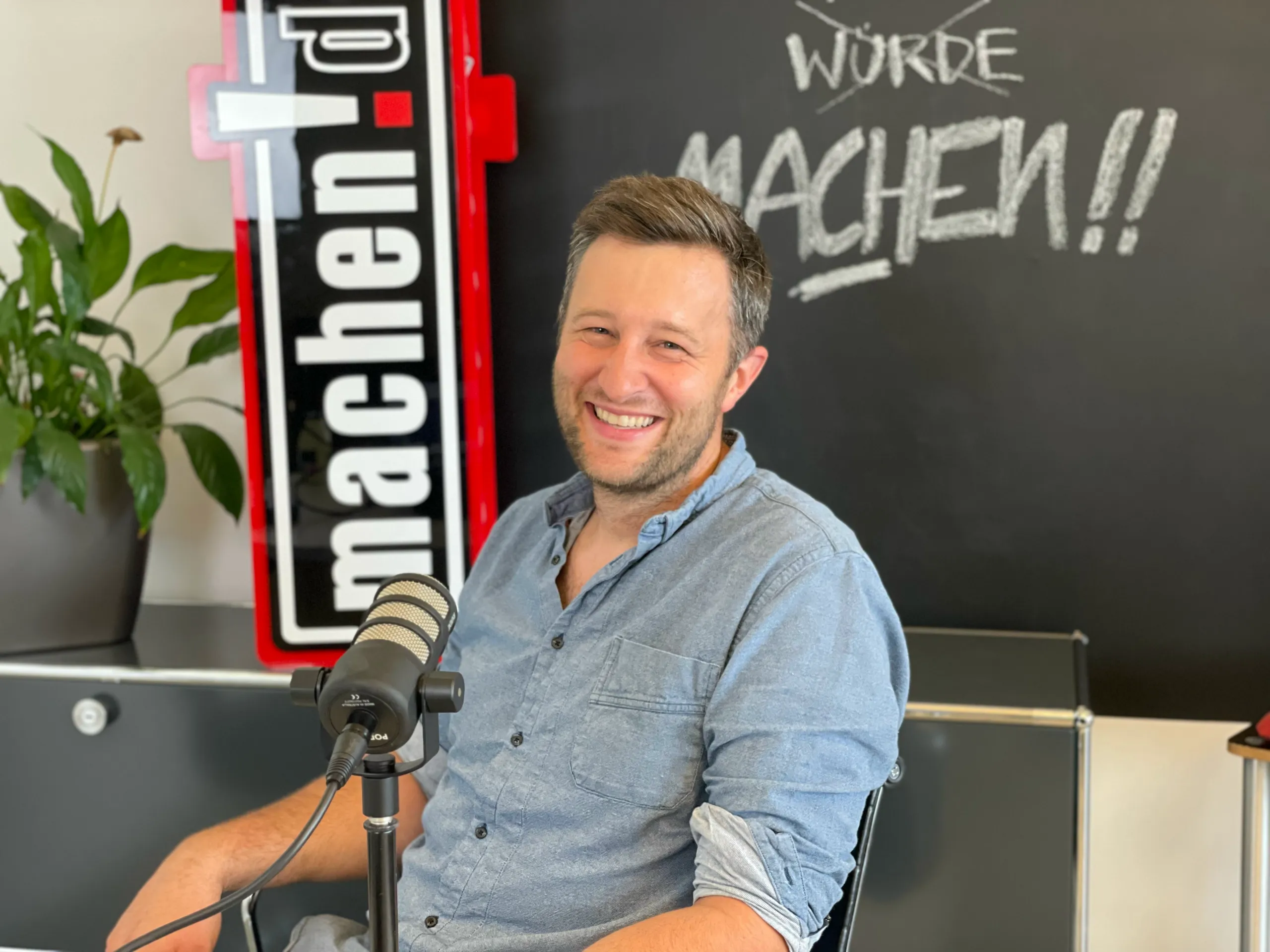 Lächelnder Mann im Podcaststudio mit Mikrofon
